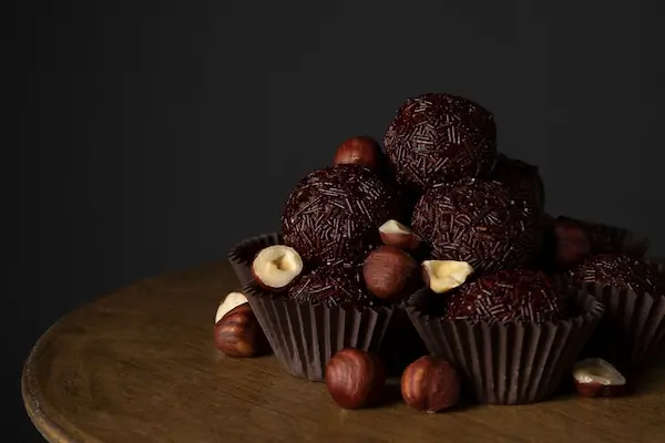 Brigadeiros gourmet decorados com avelãs, dispostos em forminhas sofisticadas
